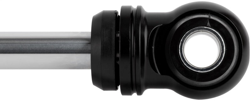 Close-up of the FOX 99+ Chevy HD 2.0 Perf Series Rear Shock, featuring a sleek black spherical rod end bearing attached to a silver rod. This component ensures durability with its fade-resistant performance, offering a circular opening for mounting and is perfect for off-road capability when used with lifts from 1.5 to 3.5 inches.