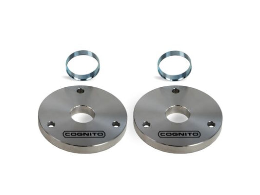 A set of silver, round metal plates engraved with "Cognito Motorsports" are arranged with two smaller metal rings against a plain white background. These components are part of the Cognito 2-Inch Standard Leveling Kit for 23-24 Canyon/Colorado AT4 and Trail Boss, offering a 1-inch lift for the AT4X and ZR2 models.