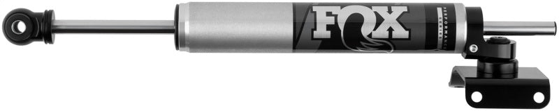 The Fox 14-18 RAM 2500/3500 2.0 Performance Series 8.3in TS Stabilizer Axle Mount, designed by FOX, features a sleek silver and black aesthetic complete with the "FOX" logo. It showcases performance-oriented valving within its lightweight aluminum cylindrical body and is equipped with mounting brackets on both ends to enhance off-road capabilities.