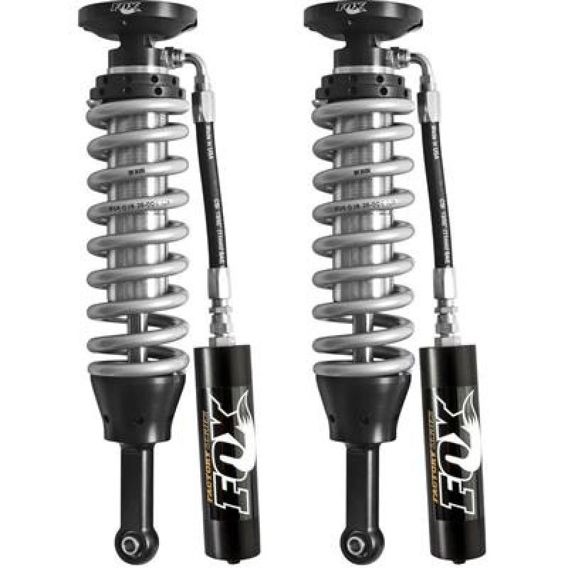 A pair of FOX 2.5 Factory Series front coilover shocks for the 2005+ Toyota Tacoma 4WD/2WD, designed for a 4-6 inch lift, featuring black and silver components with coiled springs and reservoir canisters. The FOX logo is prominently displayed on the reservoirs. These coilovers are vertically positioned side by side as part of a lift kit.