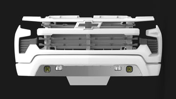 Front view of a 2022+ Chevy 1500 skid plate and valence kit by Mazzulla Offroad, showcasing a geometric grille design in white. The central logo and two round lights near the bottom are complemented by the grille's CNC-like precision, all set against a dark background.