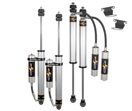 The Carli Suspension 14-23 Ram 2500 (4WD - Coil/Coil) DIESEL CARLI-SPEC 2.0" Remote Reservoir 2.5" Lift Shock Set, designed for off-road use and featuring reservoirs and mounts, is showcased against a white backdrop that accentuates its metallic and black components.