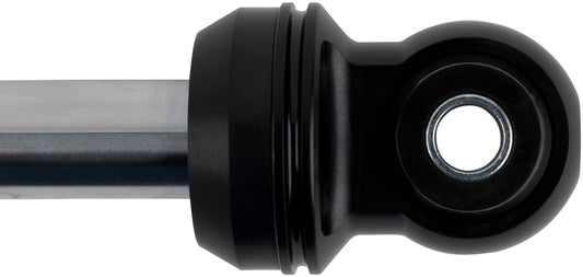 The image showcases a close-up of a black FOX Performance Elite shock absorber, specifically the Fox 2019+ Ford Ranger 2.5 Factory Series 0-1.5in Rear Remote Reservoir Shock (Pair) - Adjustable, featuring a visible metal rod on the left and a circular hole on the right end, set against a white background.