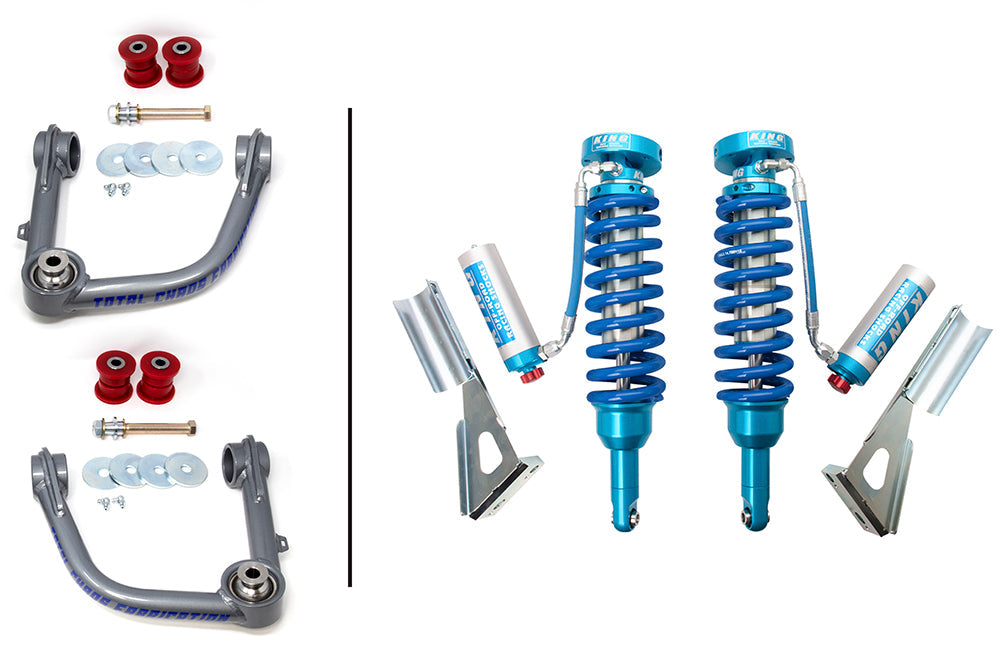 Image showing the 03-22 Toyota 4Runner Lift Kit with King 3.0 Adjustable Front Shocks by TOTAL CHAOS. On the left, two grey control arms with red bushings and various metal washers and bolts are arranged. On the right, two blue coilover shock absorbers with adjustable reservoirs and mounting brackets are displayed.