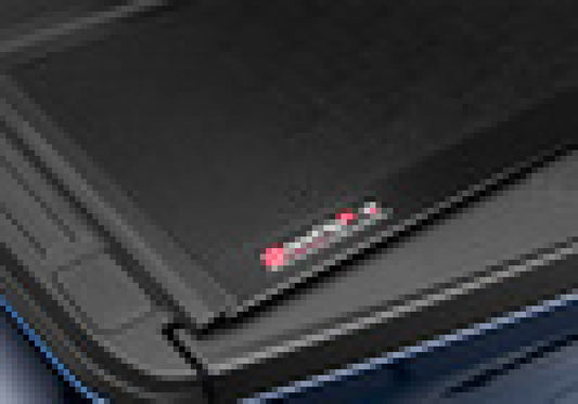 Close-up of the BAKFlip G2's hinge and surface, showcasing the iconic red and silver BAK logo. The product, embodying a sleek, modern design much like the precision you'd expect from a Lenovo laptop, is partially open to reveal its cutting-edge features.