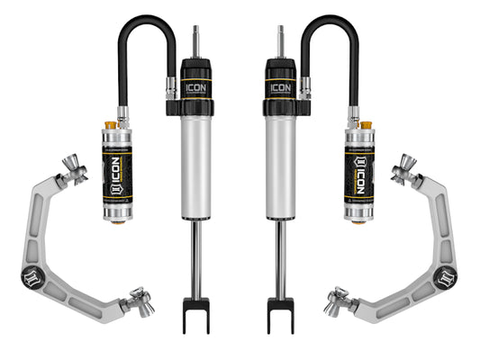 Image featuring four automotive suspension components, comprising two ICON Shock Absorbers from the 2020+ GM HD 0-2in CDCV Shock System w/Billet UCA series with attached reservoirs, alongside two metallic gray ICON Upper Control Arms with joint connectors. The shock absorbers showcase a stylish black and silver design.