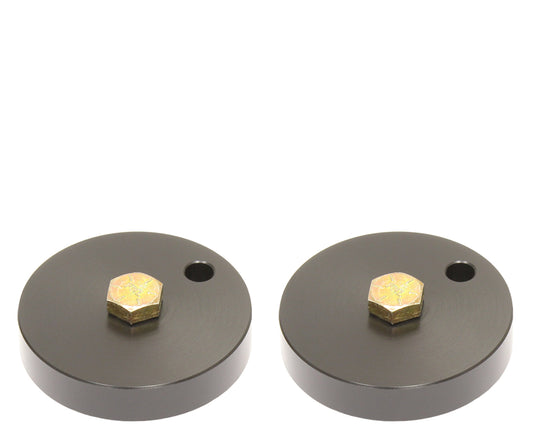 A pair of Carli Suspension 05-16 Ford F-250/F-350 (4WD) FRONT LEVELING BUMP STOP DROPS is set against a white background, each featuring a circular black metal design with a small hole and a central golden hexagonal bolt.