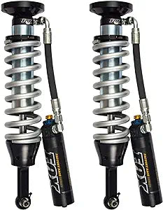 The 09-18 RAM 1500 FACTORY RACE SERIES 2.5 COIL-OVER RESERVOIR SHOCK (PAIR) - ADJUSTABLE by FOX features silver coiled springs, black canisters with gold accents, and connecting hoses. These race-proven performance components are commonly used in off-road vehicles to improve suspension and ride quality.