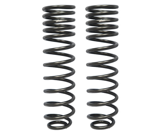 Against a white backdrop, two black coil springs from the Carli Suspension 09-18 Dodge, Ram 1500 (4WD - Coil/Coil) 0.5" Lift Rear Multi Rate Coil Spring Kit stand upright side by side, highlighting their tightly wound helical design—perfect for those considering enhancing their RAM 1500 with a rear lift kit.