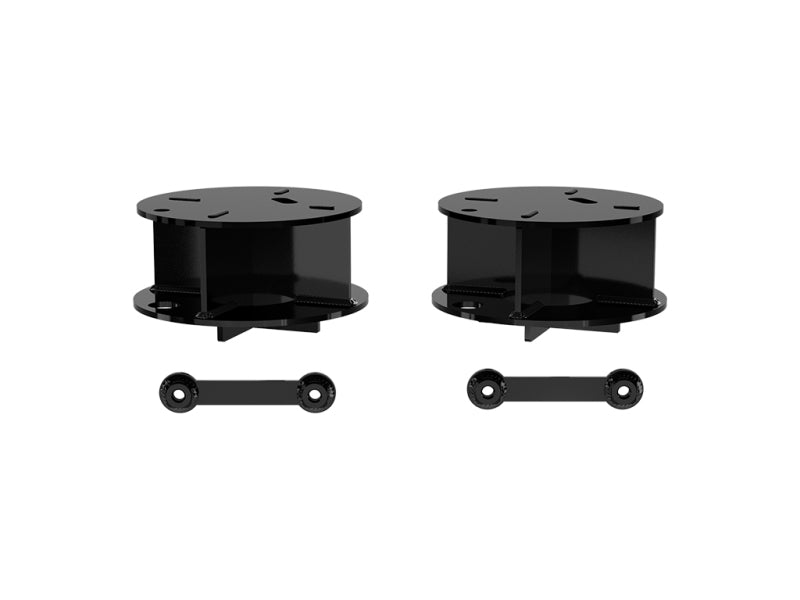 Featured in the image are two black circular stands with flat tops and short cylindrical bases, along with elongated strips containing holes for attachment. These components, reminiscent of the ICON 22 Toyota Tundra Rear Coil Spacer Kit by ICON, are showcased against a plain white background, indicating their potential use in enhancing a Toyota Tundra suspension system.