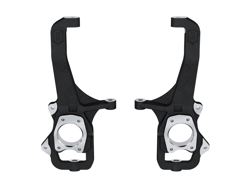 Two black and silver steering knuckles, part of the ICON 22-23 Toyota Tundra Front Knuckle Kit by ICON, are displayed side by side on a white background. These components feature a robust, industrial design with multiple attachment points and circular openings.