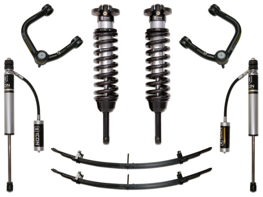 The image showcases the ICON 05-15 Toyota Tacoma 0-3.5in/2016+ Toyota Tacoma 0-2.75in Stg 3 Suspension System w/Tubular Uca, featuring two coilover springs, shock absorbers with reservoirs, and leaf springs. Notably, the set includes upper control arms equipped with Delta Joint technology for enhanced corrosion resistance, all symmetrically arranged on a pristine white background.