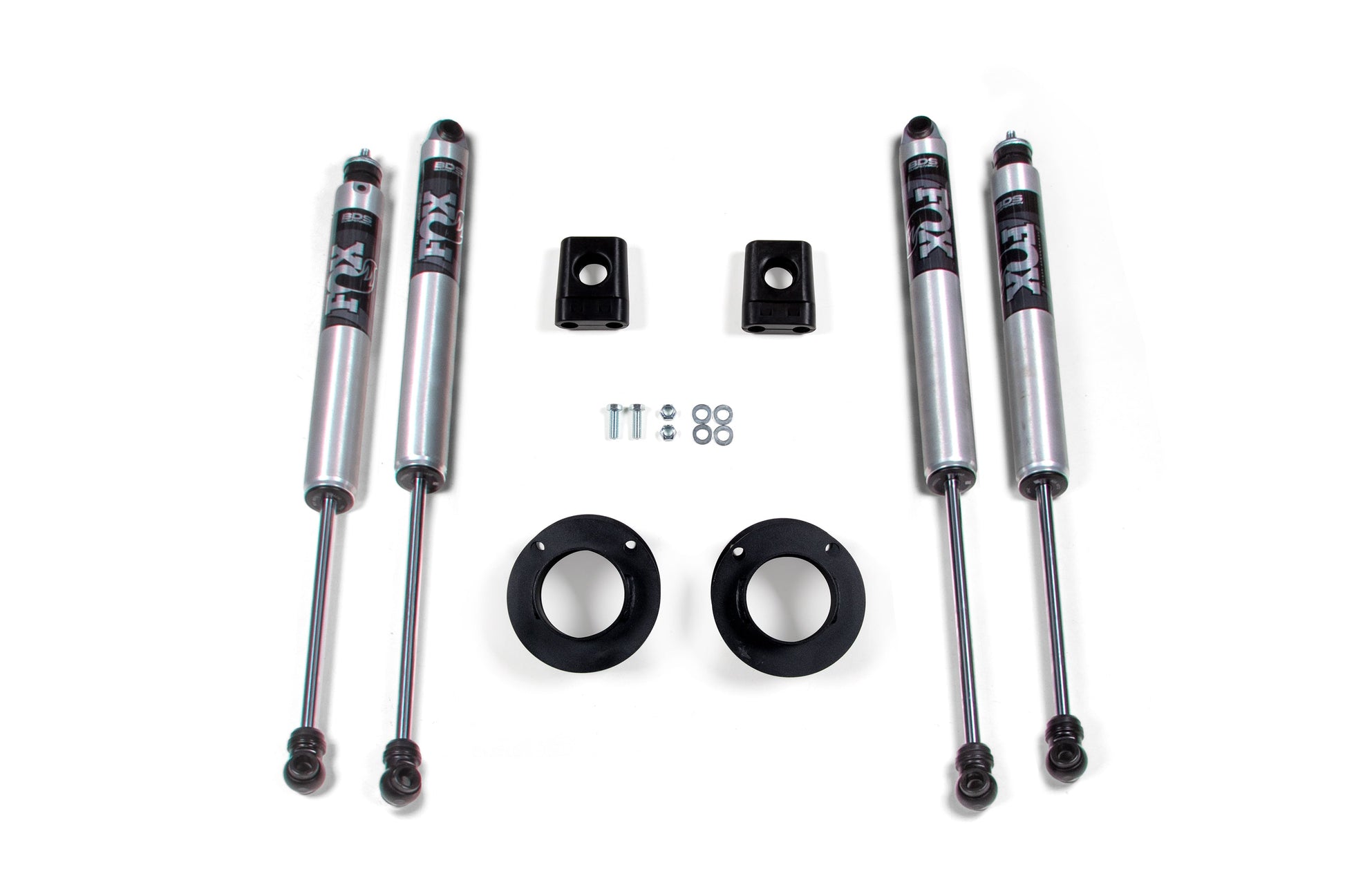 A set of four FOX 2.0 shocks, four small metal brackets, two black circular mounts, and various small screws and washers are displayed on a white background. Perfect for enhancing your RAM 3500 with this BDS leveling kit, the shock absorbers proudly bear the "FOX" brand.