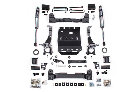 A meticulously arranged BDS 6 Inch Lift Kit designed for off-road protection on a white surface. The set, ideal for a 2005-2015 Toyota Tacoma 4WD, includes shock absorbers, brackets, bolts, a skid plate, and various mounting hardware in predominantly black and metal finishes.