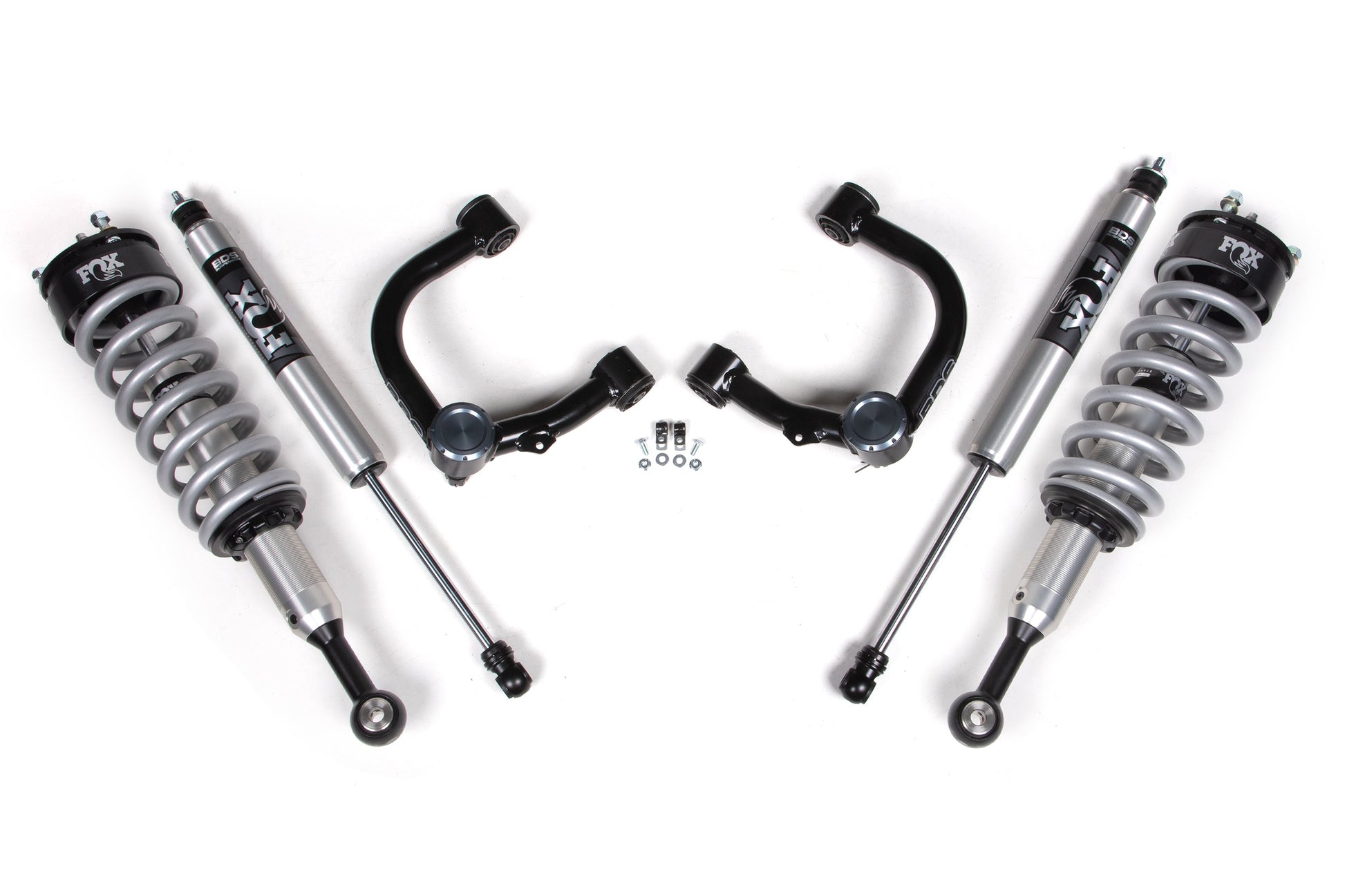 Image of a BDS 1 Inch Lift Kit for the Toyota Tacoma (2016-2023) 4WD, featuring two FOX 2.0 coil-over shocks, two upper control arms, and related hardware. The components are symmetrically arranged on a white background, showcasing parts used for off-road or performance suspension upgrades from BDS Suspension.