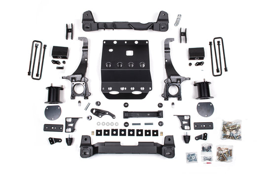 A collection of various automotive parts and components for the BDS 5.5 Inch Lift Kit, designed for a Toyota Tacoma TRD Pro (2017-2023) 4WD, laid out on a white background. The parts include metal brackets, screws, bolts, washers, spacers, and a protective skid plate. The arrangement is organized and symmetrical.