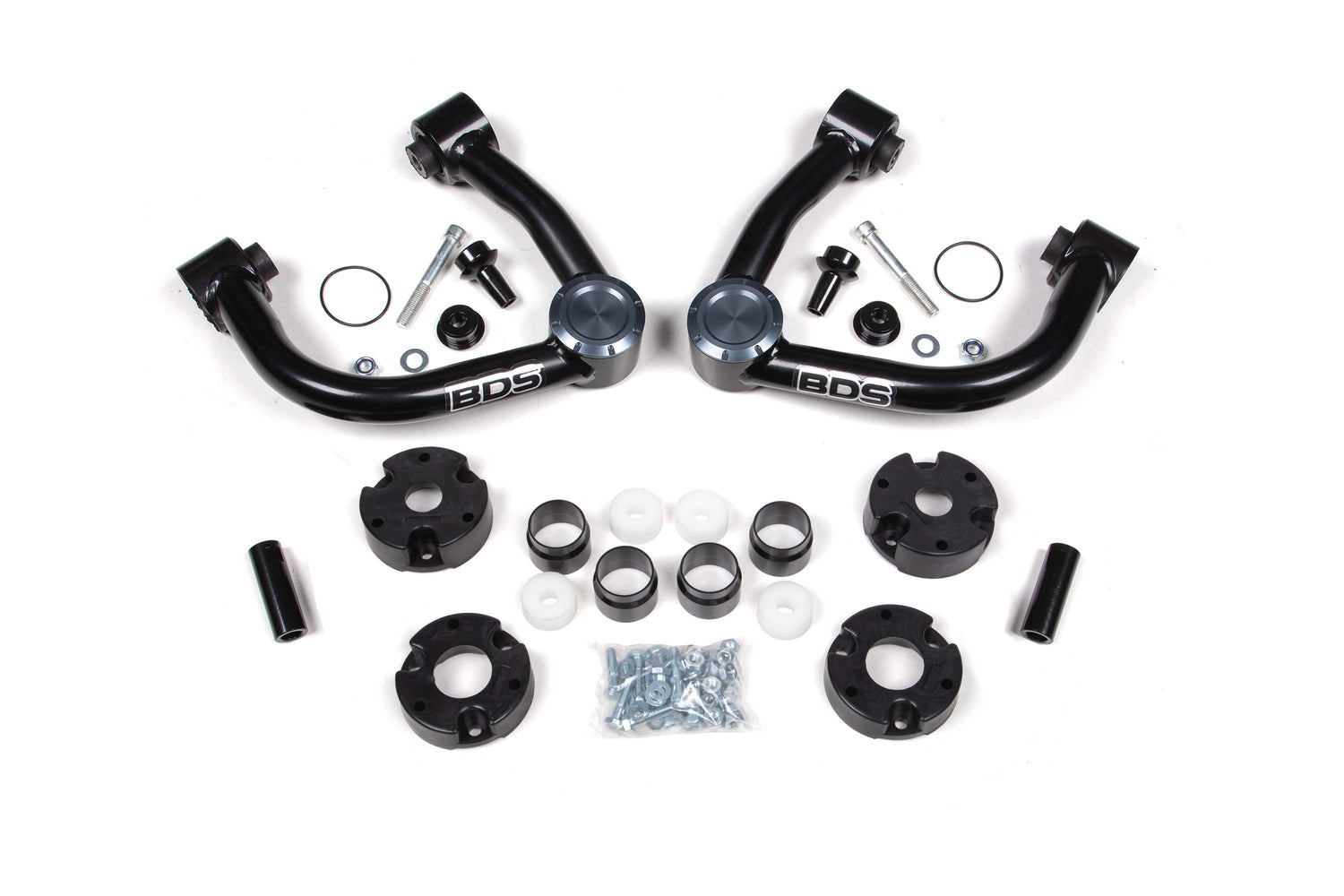 A set of black automotive suspension components on a white background, including two upper control arms with "BDS" printed on them, various bushings, spacers, a bag of bolts, and other small hardware parts designed for BDS's 4 Inch Lift Kit for the 2021-2022 Ford Bronco 2 Door Base Shock Package.