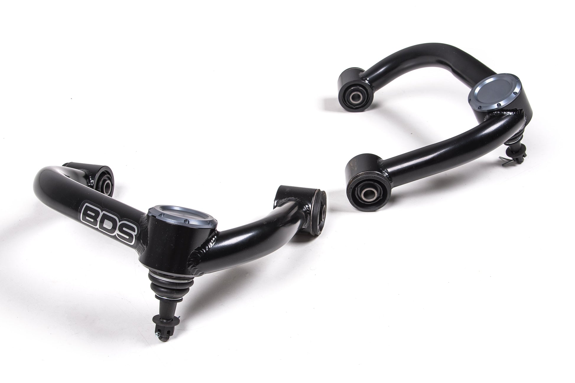 The image features two black upper control arms with bushings from the BDS brand, made of high-strength steel tubing. The left control arm has "BDS" written on it. Both arms have a shiny metallic finish at certain points and are set against a plain white background, making them ideal for leveled and lifted applications in Ford F-150 models from 2004 to 2020.