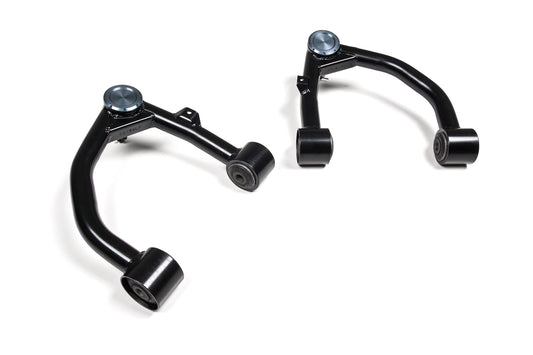 Two black metal upper control arms from the BDS Upper Control Arm Kit designed for Toyota Tundra (07-21) applications are placed on a white background. Each arm features bushings at both ends and a ball joint cap on the outer end, showcasing high-strength steel tubing ideal for leveled and lifted setups.