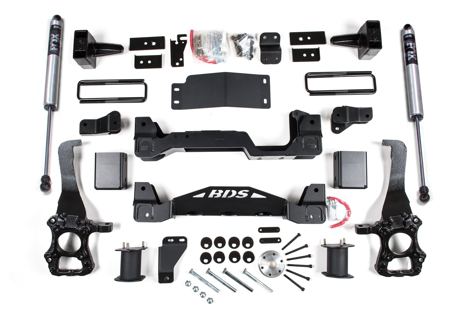 A detailed array of components for the BDS 6 Inch Lift Kit | Ford F150 (15-20) 4WD, displayed on a white background. This includes BDS-branded crossmembers, shocks, mounting brackets, bolts, spacers, and various other metal parts essential for installation. This lift kit guarantees exceptional off-road performance and protection for your Ford F150.