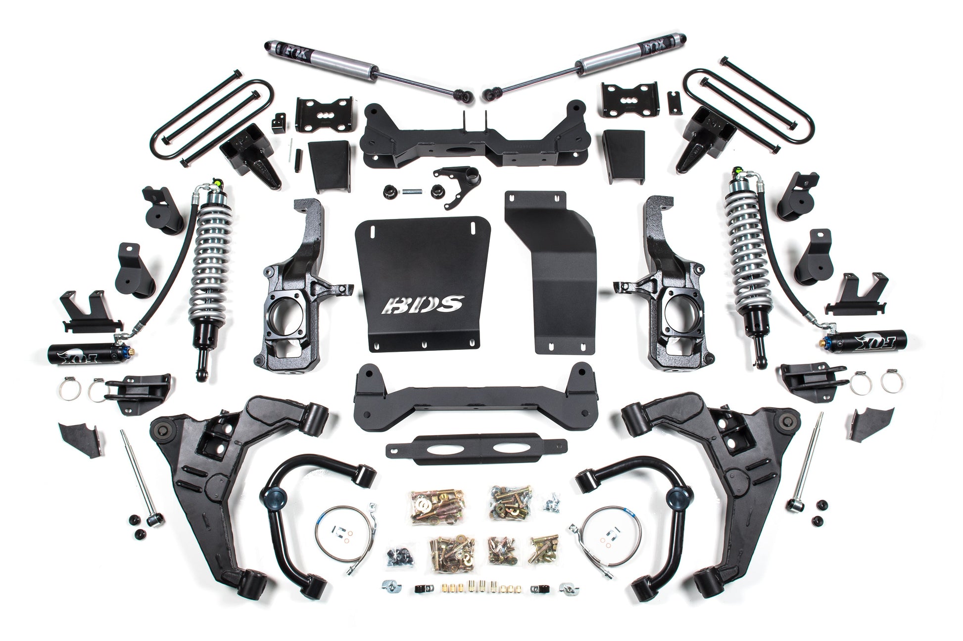 A neatly arranged display of various car suspension components on a white background. Items include coilovers, control arms, brackets, bolts, and other parts. Some parts are labeled with random letters and numbers, showcasing elements from the BDS 6.5 Inch Lift Kit | FOX 2.5 Coil-Over Conversion for Chevy Silverado or GMC Sierra 2500HD/3500HD (11-19) Diesel.