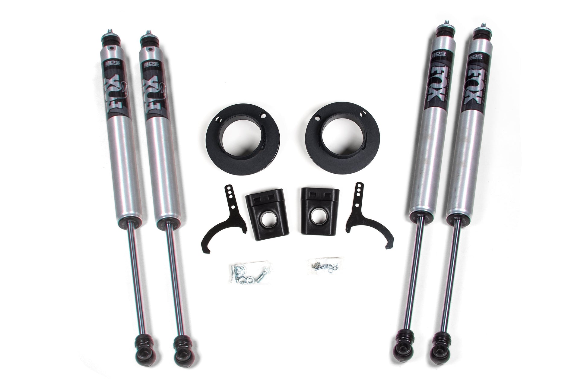 The BDS 2 Inch Lift Kit for a RAM 3500 featuring rear air ride (model years 2013-2023) includes an array of vehicle suspension components such as four FOX 2.0 silver shock absorbers with black and white branding, two black mounting brackets, two circular mounts, two U-shaped tools, and various nuts and bolts.