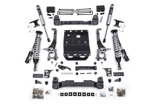 A neatly arranged collection on a white background showcases various automotive suspension system components from the BDS 6 Inch Lift Kit with FOX 2.5 Coil-Over for the Toyota Tacoma (16-23) 4WD. The array includes control arms, brackets, bolts, and hardware. Each item is positioned in an orderly manner, highlighting its unique shape and function.