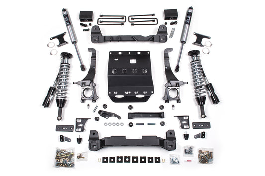 A variety of metal car parts and components from the BDS 6 Inch Lift Kit for Toyota Tacoma (05-15) 4WD, including FOX 2.5 Coil-Over shocks, springs, mounting brackets, screws, and hardware, are neatly arranged on a white background. The parts are symmetrically organized, showcasing their details and structure.