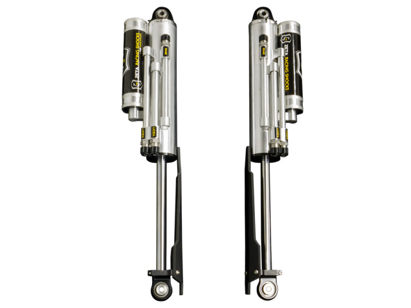 A pair of ICON 10-14 Ford Raptor Rear 3.0 Zeta Series Shocks PB is positioned side by side on a white background, evoking a sense of Ford SVT Raptor Shocks. Designed for automotive or off-road vehicles, these silver shocks feature attached black and yellow reservoirs and boast easy-to-adjust knobs to deliver optimal suspension performance.