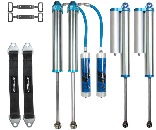 The image showcases a set of Carli Suspension's Performance 2.5 Shock Set for the 03-12 Dodge Ram 2500 and 03-13 3500 (4WD) with Long Arm Valving, featuring blue and silver shock absorbers, metal brackets, and black Corbeau straps meticulously arranged against a white background. The components are symmetrically and precisely organized, embodying the high-quality standards associated with Carli products.