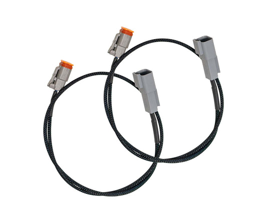 Two black braided cables are depicted, each featuring gray and orange connectors on both ends. Coiled in a circular shape, these cables resemble the Carli Suspension EVENTURE Long Bed Extension Harness, ideal for automotive or electronic applications such as those involving 17-23 Ford F-250/F-350 4WD setups.