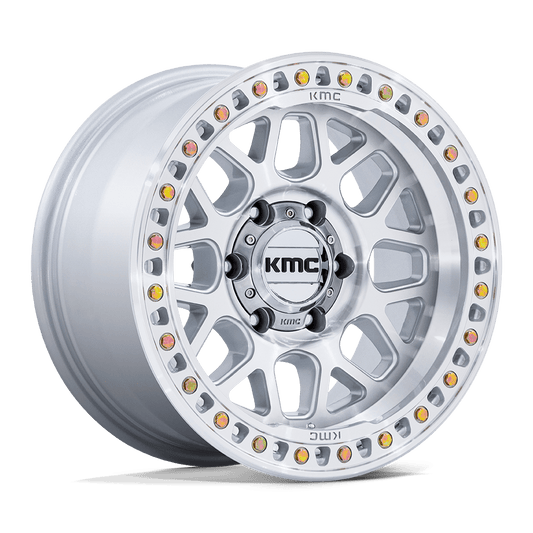 A sleek KM549 GRS Gloss Silver wheel from KMC displays a bold logo at its center. The machined face is adorned with intricate cutouts and a circular arrangement of bolts, complemented by decorative yellow and red accents along the outer rim, enhancing the gloss of these striking silver wheels.