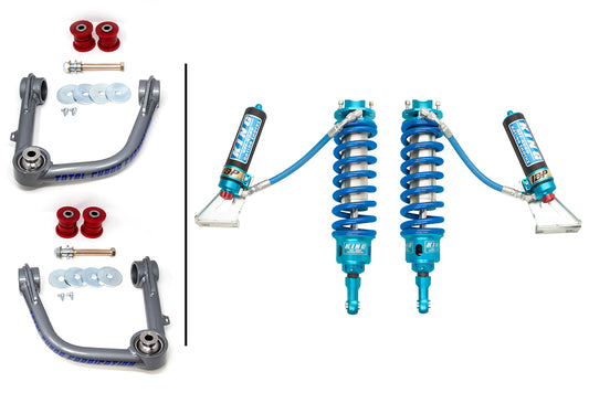 Image showcasing car suspension components: two grey upper control arms with bushings and bolts on the left, and two blue King 3.0 adjustable front shocks with external reservoirs on the right. The parts are neatly arranged, highlighting their design and detail—perfect elements from the TOTAL CHAOS 07-09 Toyota FJ Cruiser Lift Kit.