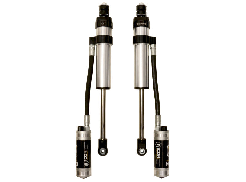 A pair of ICON 2005+ Ford F-250/F-350 Super Duty 4WD 0-2.5in Front 2.5 Series Shocks VS RR CDCV features metallic cylindrical bodies and black hoses with connected reservoirs branded "ICON" and detailed technical specifications, ensuring a smooth ride and enhanced off-road performance for vehicle suspension systems.