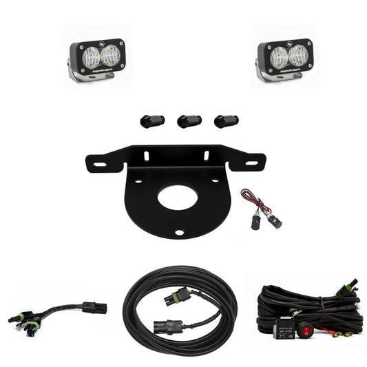 The Baja Designs 2021+ Ford Bronco Dual S2 Sport W/C Reverse Kit w/Upfitter includes two Baja Designs Dual S2 Sport LED lights, a black metal mounting bracket, three spacers, several cables and connectors, and a small black control unit with a red on/off switch. The components are arranged on a white background.