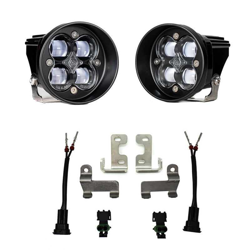 Presenting the Baja Designs 12-21 Toyota Tacoma/Tundra/4Runner (Excl Limited) Squadron-R Fog Pocket Light Kit, featuring two black, circular LED fog lights with intricately designed lenses. The kit also includes silver mounting brackets, black wire connectors, and additional hardware components, all showcased against a white background. Ideal for your Toyota Tacoma, this complete kit from Baja Designs ensures you have all the necessary parts ready to enhance your vehicle.