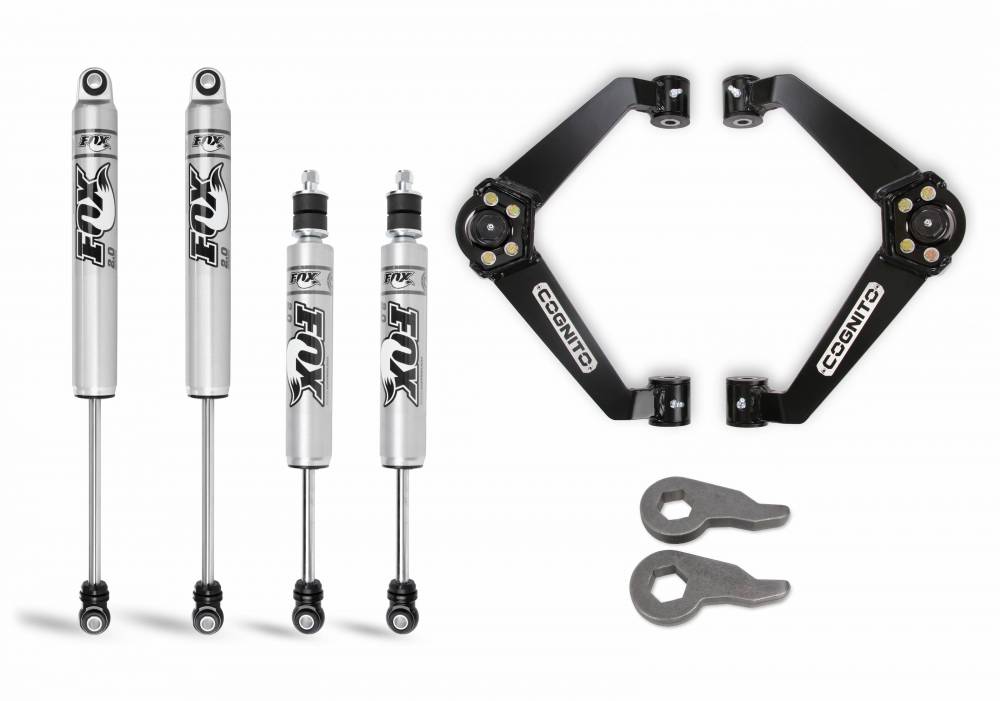 Image of a Cognito Motorsports 3-Inch Performance Leveling Kit With Fox PS 2.0 IFP Shocks for 01-10 Silverado/Sierra 2500-3500 2WD/4WD, featuring four silver Fox Performance Series Monotube Shocks with black and white branding, two black Cognito upper control arms, and two gray torsion keys. The components are arranged neatly against a white background.