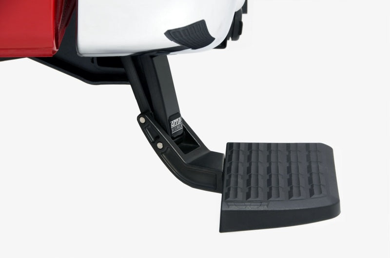 Close-up view of an AMP Research 2015-2018 Ford F150 BedStep - Black deployed to provide easier access to the truck bed. The retractable bumper step has a textured, non-slip surface and is attached under the truck's rear bumper.