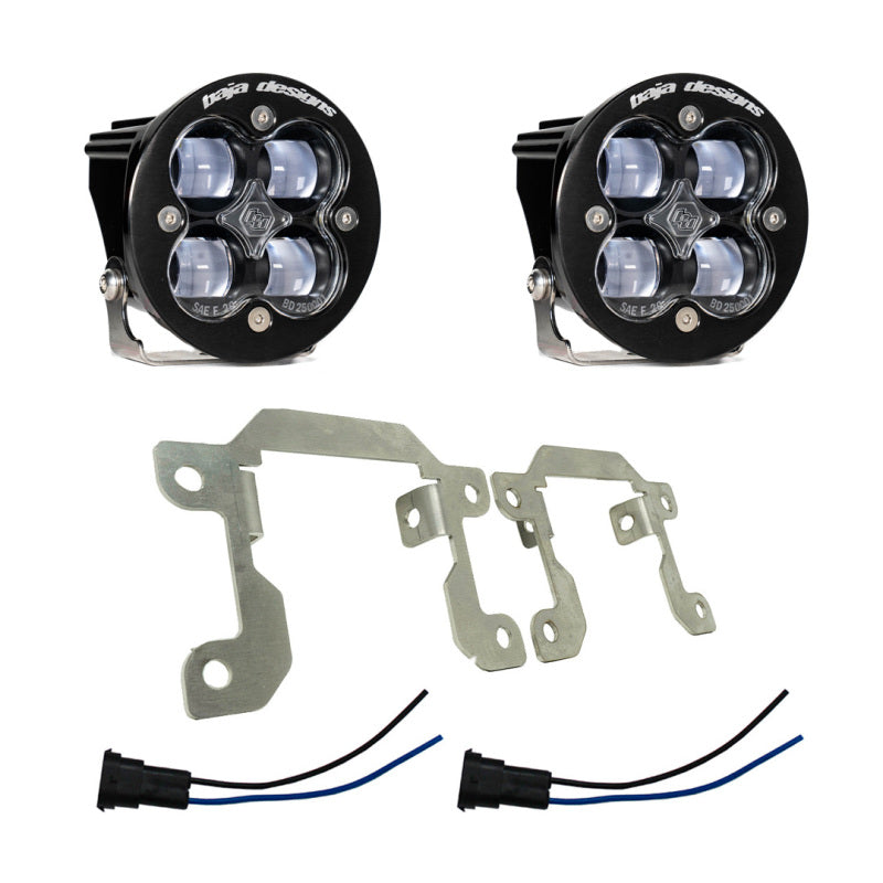 The image shows a pair of Baja Designs 2019+ Ram 2500/3500 Big Horn Fog Pocket Kit - Clear aftermarket LED off-road lights, featuring black housing, clear lenses, and four light emitters each. Below the lights are metal mounting brackets and electrical connectors with blue and black wires, specifically designed for vehicle installation in a Ram 2500/3500.