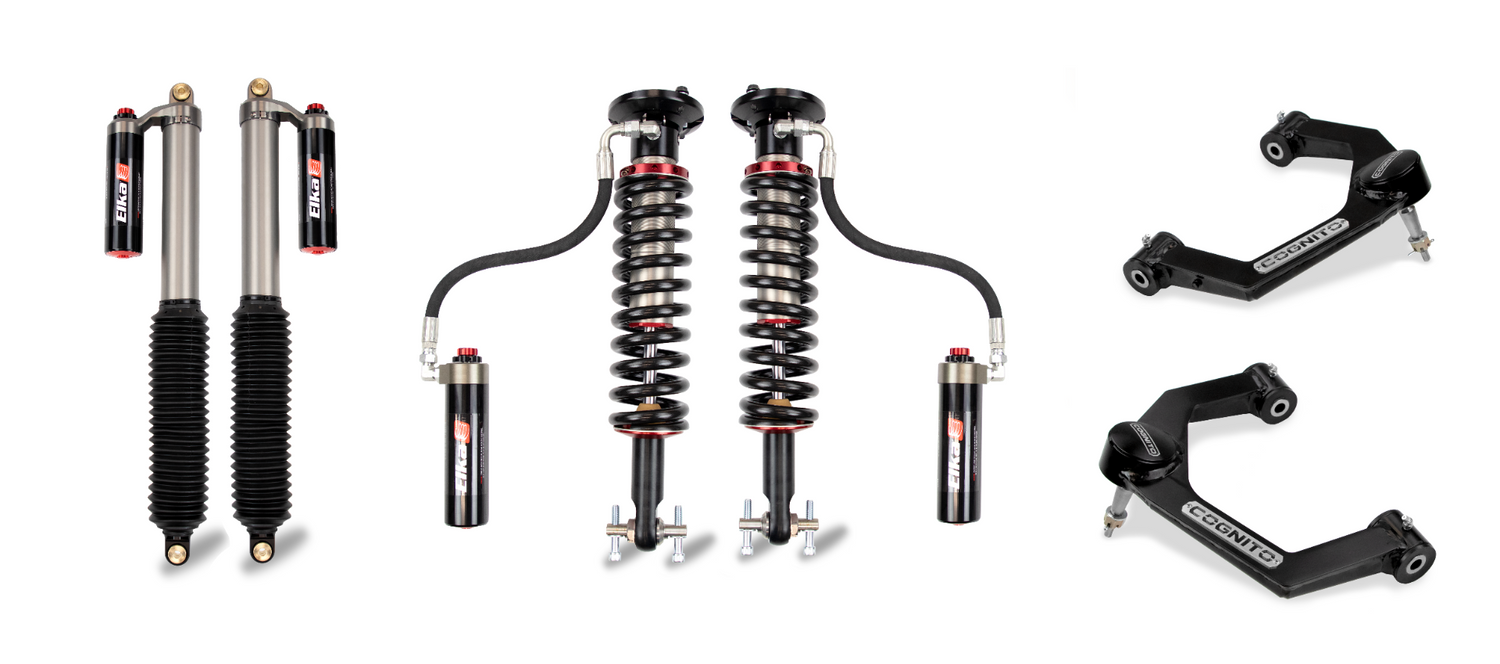 Image of off-road vehicle suspension components laid out on a white backdrop. The items include a pair of Elka 2.5 shocks with reservoirs, a pair of coilover shocks with reservoirs, and a pair of upper control arms labeled "ICONVEHICLES." These components are part of the Cognito Motorsports 2.5-Inch Elite Leveling Kit with Elka 2.5 Reservoir Shocks, suitable for 2015-2023 Ford F-150 4WD models and compatible with the Cognito Uniball Leveling Kit.