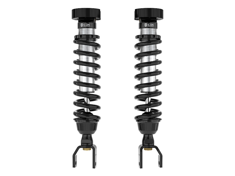 Two ICON 19-UP Ram 1500 2-3in 2.5 VS IR Coilover Kit shocks stand upright against a white background. Each black ICON shock features a coil spring wrapped around a central cylinder with mounting brackets at the bottom and adjustment knobs for lift height adjustability at the top. The shocks are identical in design.