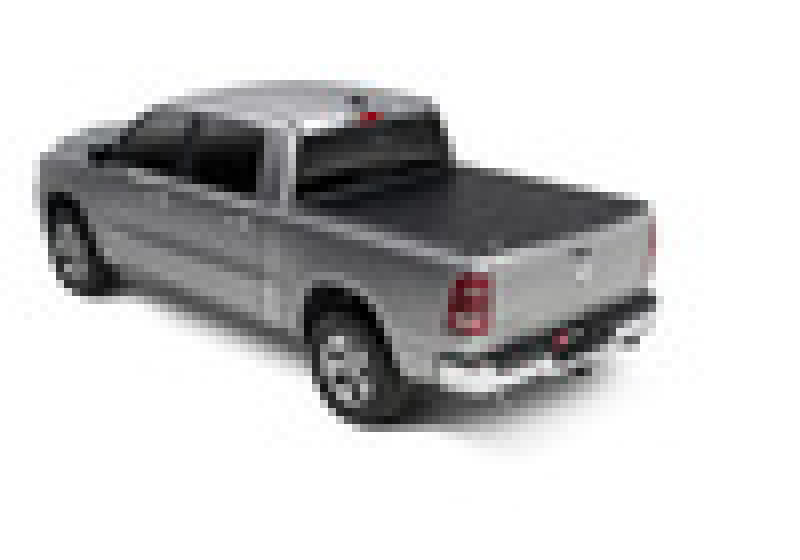 A pixelated image of a silver Dodge Ram 1500 (New Body Style without Ram Box, 2019-2020 model) pickup truck viewed from the rear-right side. The vehicle features a BAK 5ft 7in Bed Revolver X2 aluminum roll-up cover on its cargo bed and black-tinted windows.