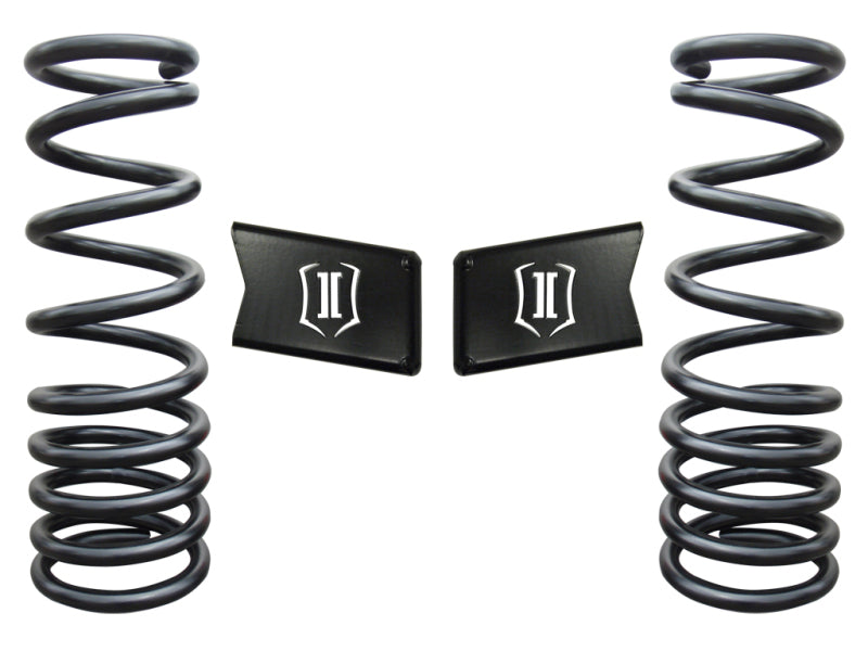 Two black coil springs are positioned vertically on each side of the image, flanked by two black rectangular metal pieces with a white 'II' logo in the center. The ICON 03-12 Dodge Ram HD 4WD 4.5in Dual Rate Spring Kit is arranged symmetrically against a white background. Perfect for enhancing the performance of your Dodge Ram 4WD.