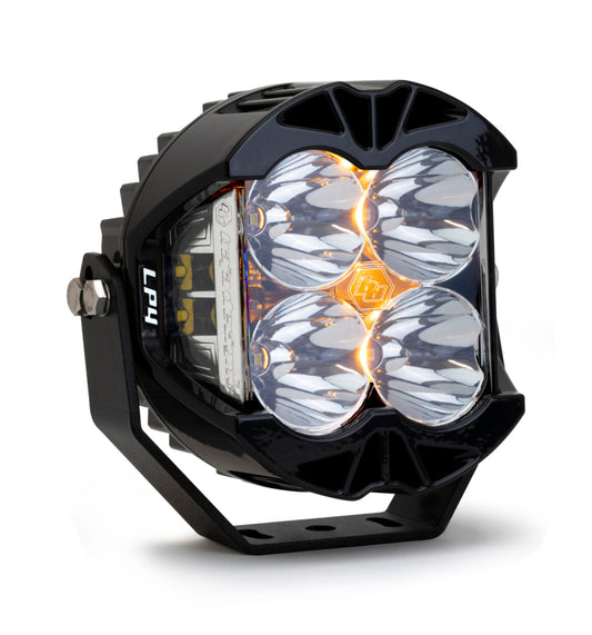 Presenting the Baja Designs LP4 Pro Spot LED - Clear: a black, square-shaped off-road light with the iconic Baja Designs logo prominently displayed in the center. It features four circular lenses, a sturdy ribbed casing, and includes a side mounting bracket designed for rugged outdoor adventures.