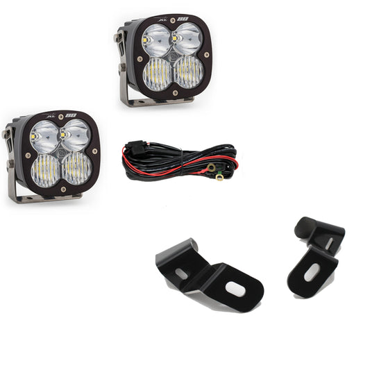 Image of the Baja Designs XL 80 Driving Combo A-Pillar Kit for a 2019+ Ram 2500/3500, featuring two square LED lights, a wiring bundle, and two black metal brackets with mounting holes. The LED lights consist of multiple smaller bulbs within a black casing.