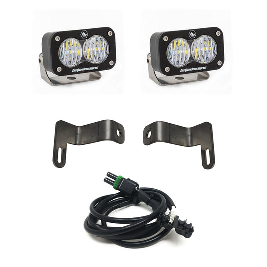 The Baja Designs 2019+ Ram Rebel S2 Dual Reverse Kit includes two compact LED light pods with mounting brackets and an electrical wiring harness. Each light pod features a black frame with dual round LED lights and the brand name "Baja Designs" prominently displayed on the front. Perfect for your Ram Rebel, the brackets and wiring harness are neatly arranged in front of the pods.