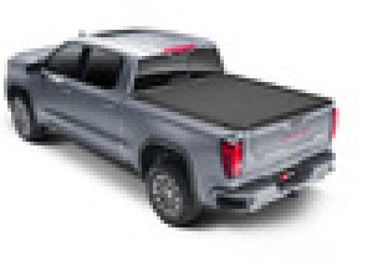 A pixelated image of a gray pickup truck with a BAK 19-21 GM Sierra 1500 (Carbon Pro Bed Cover) Revolver X4s 5.9ft Bed Cover from BAK over the cargo bed, viewed from the rear and slightly to the left.