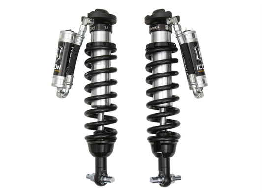 The ICON 2019+ Ford Ranger Ext Travel 2.5 VS RR Coilover Kit is a pair of black remote reservoir coilover shocks designed by ICON Vehicle Dynamics for advanced vehicle suspension systems. Each shock features a spring coil around a cylinder and a branded reservoir attached via a hose, with the "ICON" logo prominently displayed.