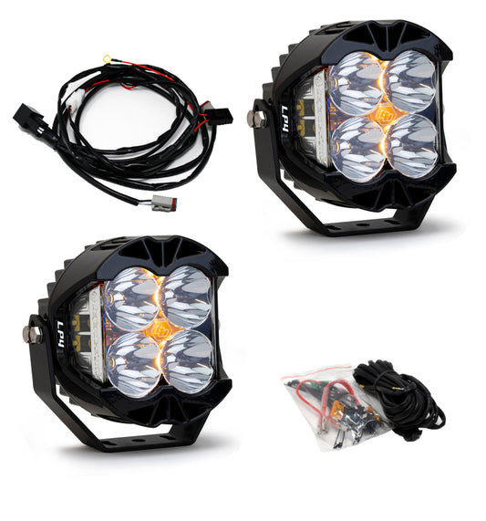 Three black LPI off-road LED lights, including the Baja Designs LP4 Pro Spot LED - Clear Pair, feature multiple lenses and come with wiring harnesses and connectors. This set contains two lights along with additional cables in durable plastic packaging.