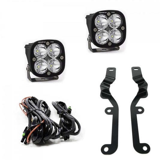 The image showcases a pair of square LED off-road lights, specifically the Baja Designs 2019 Silverado 1500 Squadron Pro A-Pillar Kit. Each light features four bulbs, mounting brackets, and accompanying wiring harnesses. The components are arranged on a white background.